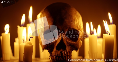 Image of Candles and human skull in darkness closeup footage