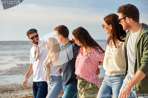 Image of happy friends walking along summer beach