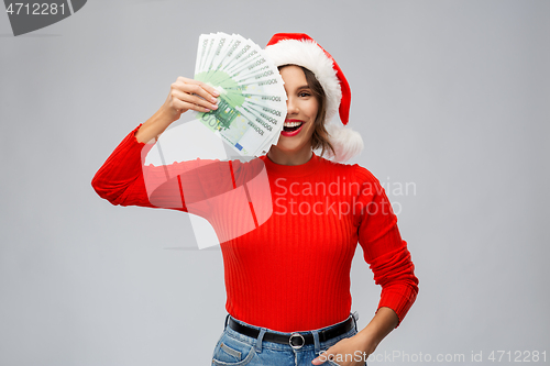 Image of happy woman in santa hat with money on christmas