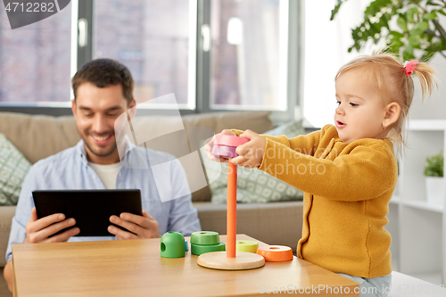 Image of father with tablet pc and baby daughter at home