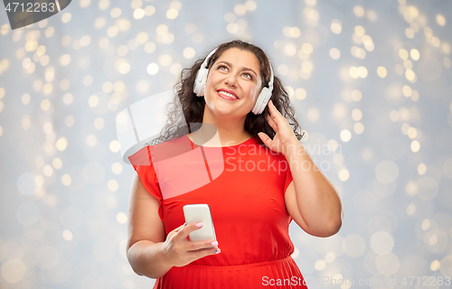 Image of woman in headphones listens to music on smartphone