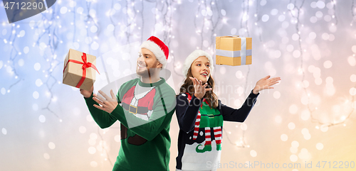 Image of happy couple in christmas sweaters with gifts