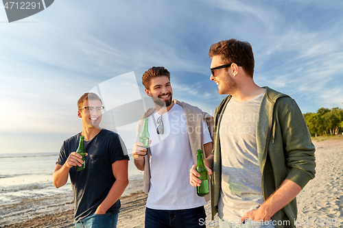 Image of young men with non alcoholic beer walking on beach