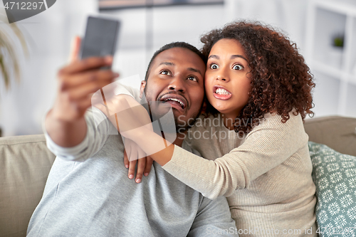 Image of couple with smartphone taking selfie at home