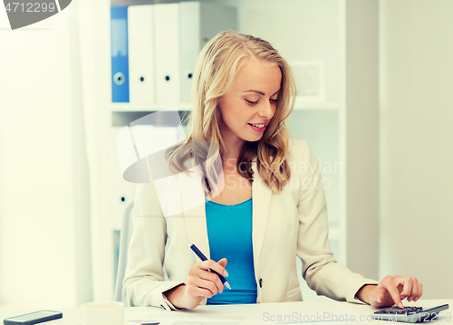 Image of businesswoman with calculator counting at office