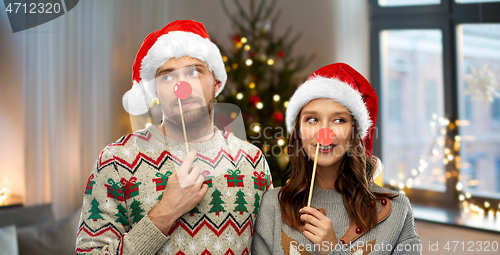 Image of couple with christmas party props in ugly sweaters