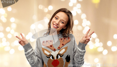 Image of woman in ugly christmas sweater showing peace sign