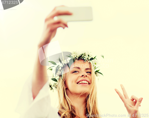 Image of woman taking smartphone selfie and showing peace