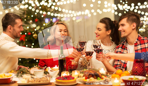 Image of happy friends drinking red wine at christmas party