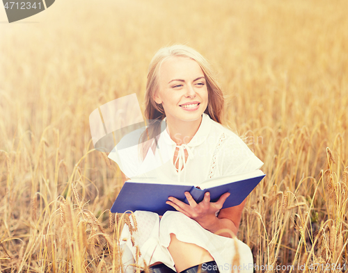 Image of smiling young woman reading book on cereal field