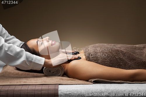 Image of beautiful woman having hot stone massage at spa