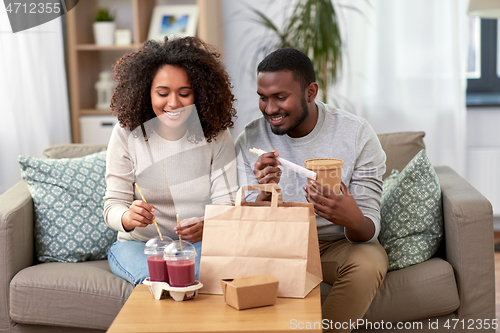 Image of happy couple with takeaway food and drinks at home