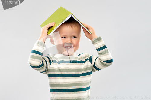 Image of portrait of smiling boy with book on head