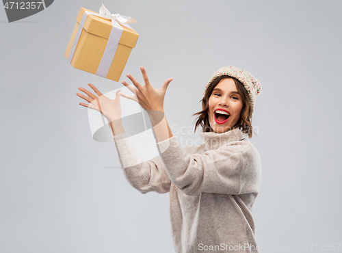 Image of young woman in winter hat catching gift box