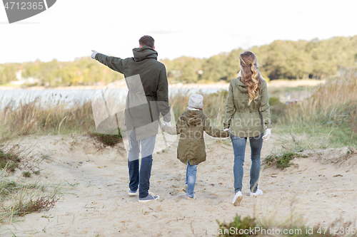 Image of happy family walking along autumn beach