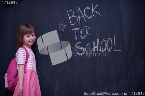 Image of school girl child with backpack writing  chalkboard