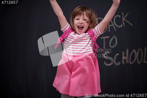 Image of school girl child with backpack writing  chalkboard