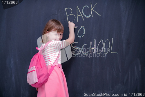 Image of school girl child with backpack writing  chalkboard