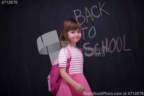 Image of school girl child with backpack writing  chalkboard