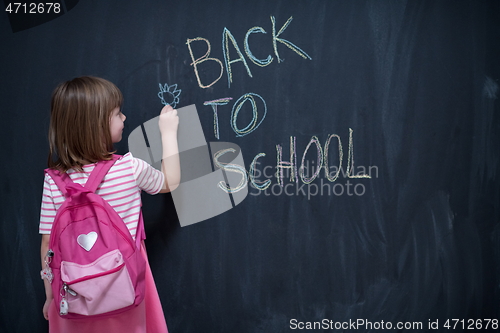 Image of school girl child with backpack writing  chalkboard