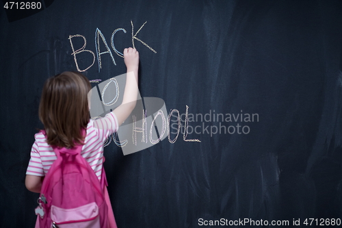 Image of school girl child with backpack writing  chalkboard