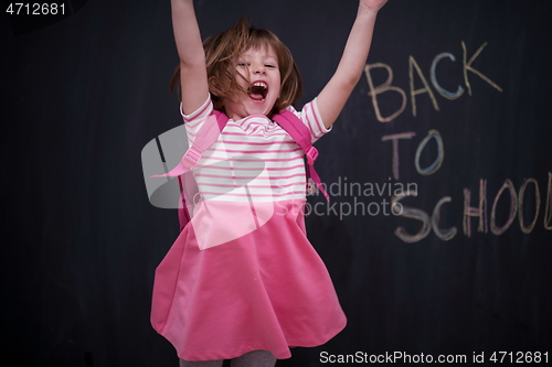 Image of school girl child with backpack writing  chalkboard