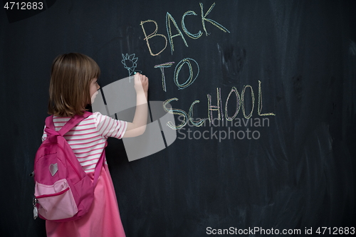 Image of school girl child with backpack writing  chalkboard