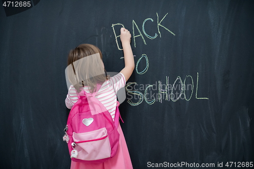 Image of school girl child with backpack writing  chalkboard