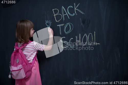 Image of school girl child with backpack writing  chalkboard