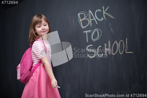 Image of school girl child with backpack writing  chalkboard