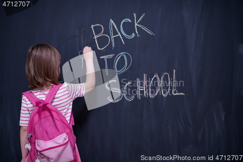 Image of school girl child with backpack writing  chalkboard