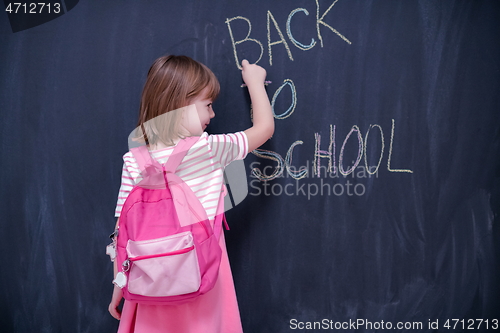 Image of school girl child with backpack writing  chalkboard