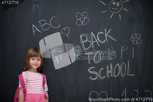 Image of school girl child with backpack writing  chalkboard