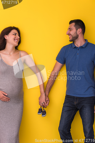 Image of couple holding newborn baby shoes