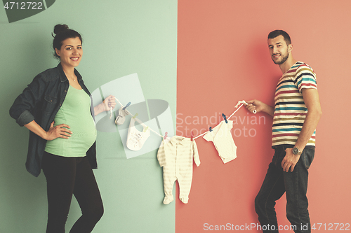 Image of young couple holding baby bodysuits