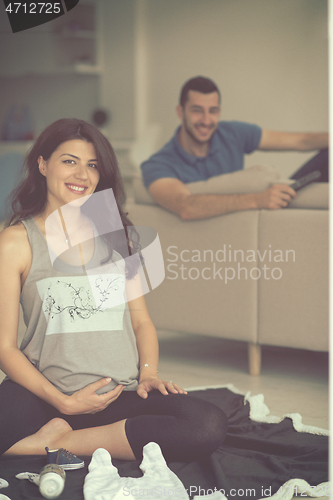 Image of pregnant couple checking a list of things for their unborn baby