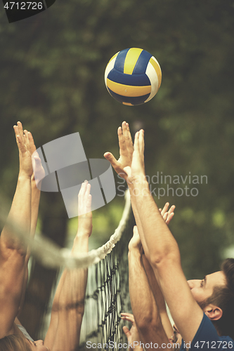 Image of group of young friends playing Beach volleyball