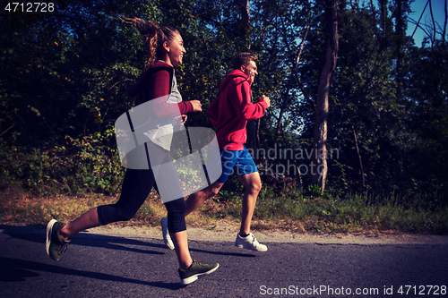 Image of young couple jogging along a country road