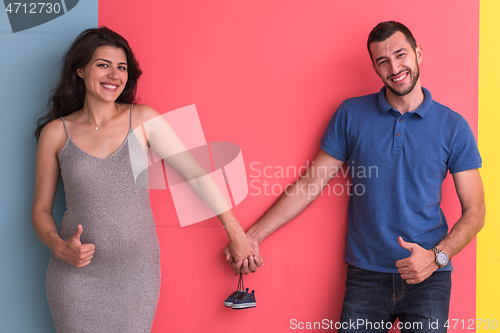 Image of young happy couple holding newborn baby shoes