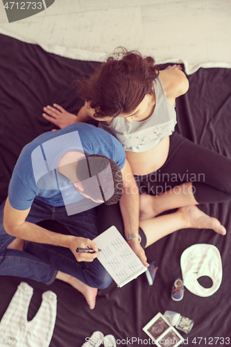 Image of top view of couple checking a list of things for their unborn ba