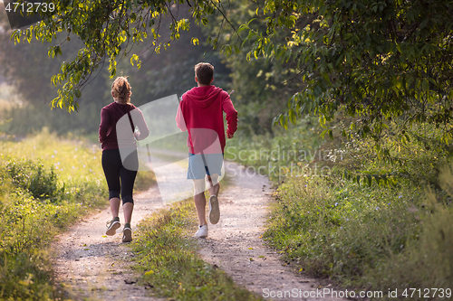 Image of young couple jogging along a country road