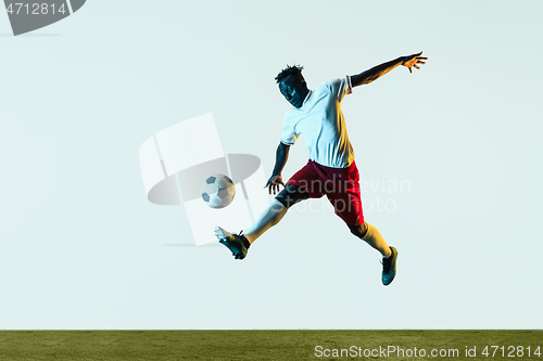 Image of Male soccer player kicking ball isolated on white background