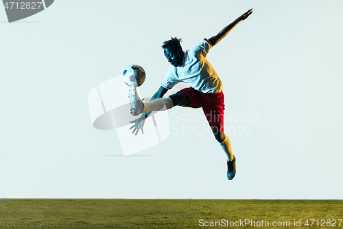 Image of Male soccer player kicking ball isolated on white background