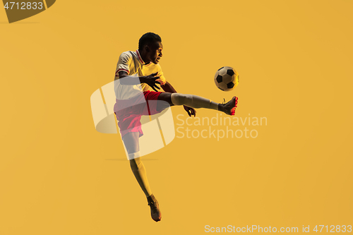 Image of Male soccer player kicking ball in jump isolated on gradient background