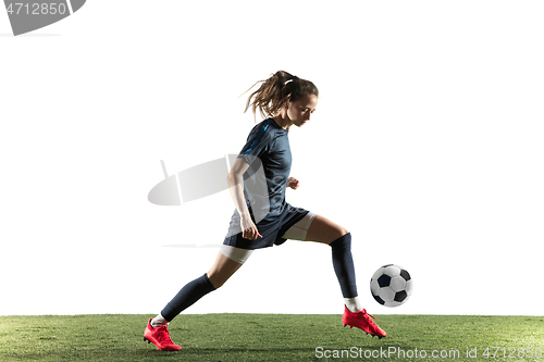 Image of Female soccer player kicking ball isolated over white background