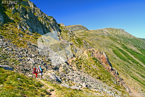 Image of Summer mountain scene, hiking tourists on trail.