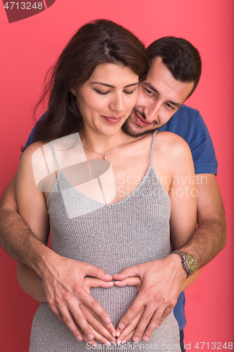 Image of pregnant  couple showing heart with their hands