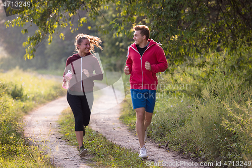 Image of young couple jogging along a country road