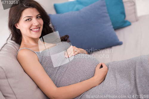 Image of pregnant woman sitting on sofa at home