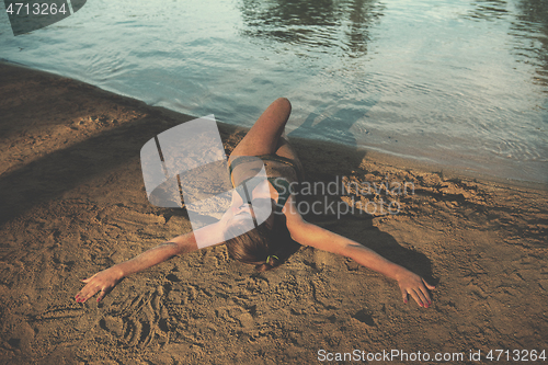 Image of girl in a green bikini relaxing on the riverbank